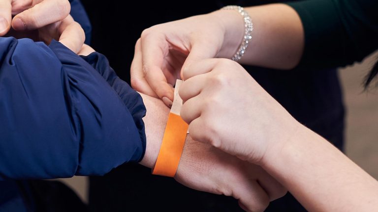 Woman putting a wrist band on a person