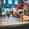 Young people having fun drinking beer at bar restaurant - Soft focus on right girl hand holding glass