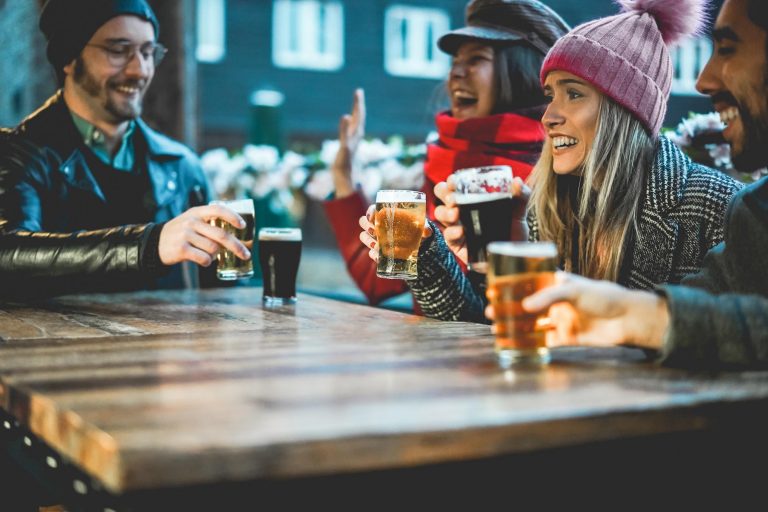 Young people having fun drinking beer at bar restaurant - Soft focus on right girl hand holding glass