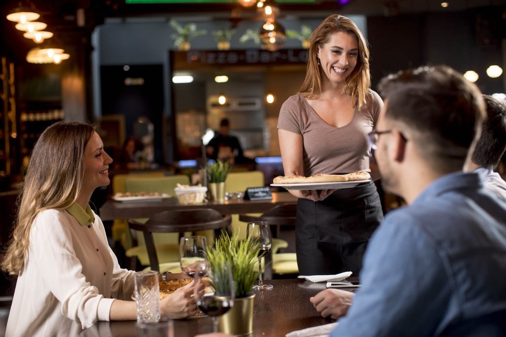 Waiter woman serving group of friends 