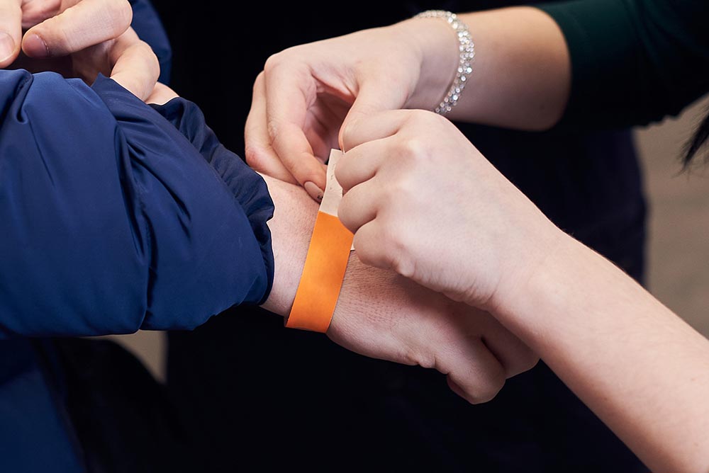 Woman putting a paper bracelet ticket on mans hand