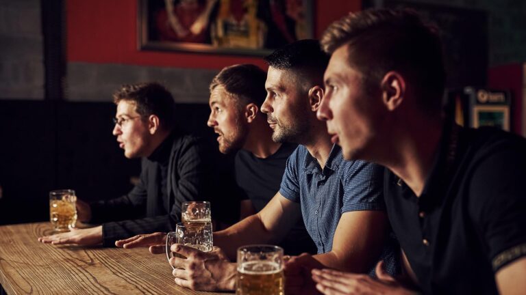 Sports fans in a bar watching a game with beer in hands