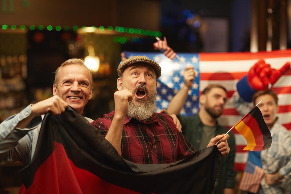 flag cheering for their football team while watching match in sport bar with American fans in the background