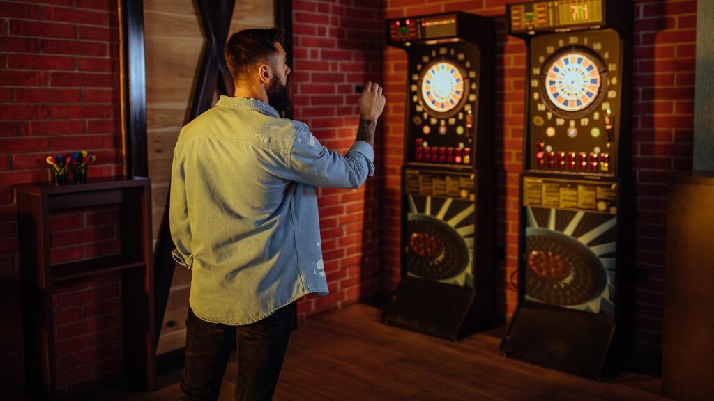 A man is aiming before taking a shot while playing darts
