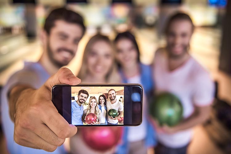 A man holding a phone taking a Bowling selfie