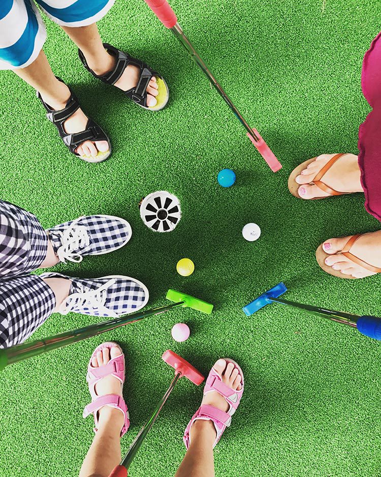 Players of mini golf with their shoes and balls on the green