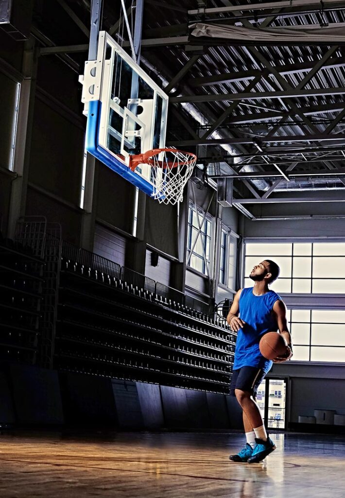 Basketball Player in Blue Jersey stands under backboard ready for a layup