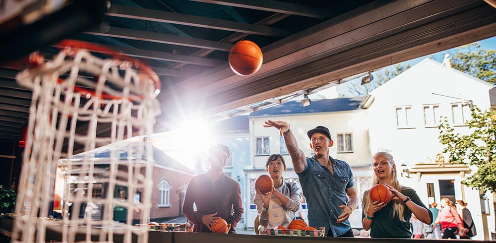 Friends shooting hoops at carnival game