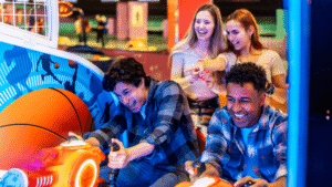 An arcade game with men playing and women watching