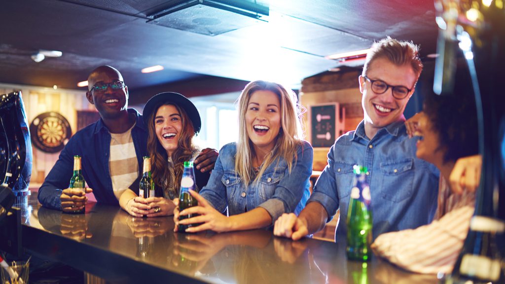 Group of friends laughing and socializing together at a bar.
